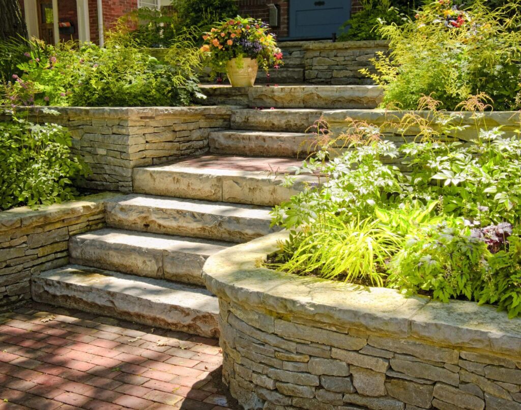 Natural stone steps and retaining walls surrounded by lush garden plants - Cajun Care Demolition & Tree Service in New Orleans